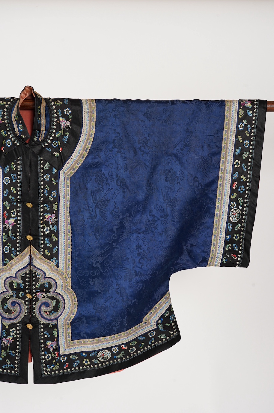 A late 19th century Chinese blue silk damask jacket, woven with Phoenix and auspicious symbols. The jacket edged with ornate rows of braiding and silk embroidery, the interior with original pink silk lining. The jacket f